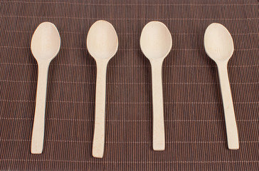 Four wooden spoons on a dark bamboo canvas. View from above. Empty spoons on the canvas.