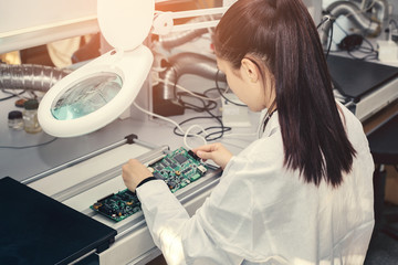 Beautiful female computer expert professional technician examining board computer in a laboratory...
