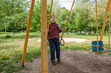 child boy playing on the Playground, riding on a swing.
