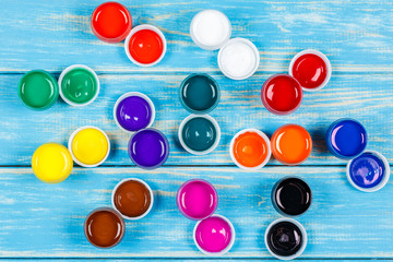 Mixed open cans of paint on a blue wooden background