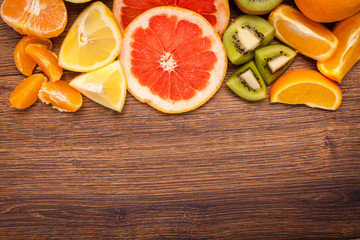 lemon, orange, kiwi, grapefruit, mandarin on a wooden surface. arrangement of sliced fruit. Top view with copy space for text