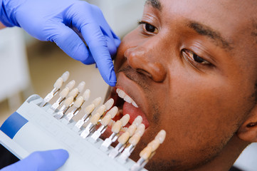 Check and select the color of the teeth. Dentist makes the process of treatment in dental clinic.