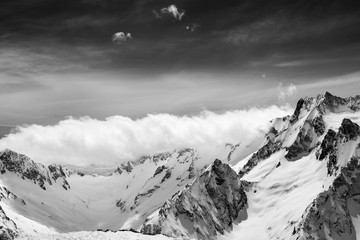 Black and white view on snow sunlight mountains in clouds