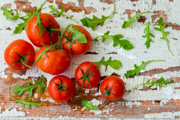 Fresh organic ripe tomatoes, basil leaves on wooden old shabby vintage table. Top view with copy space. Healthy eating concept, antioxidant, diet