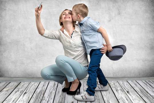 Young mother and son are photographed on a mobile phone ,making selfie .Stylish,trendy,modern	