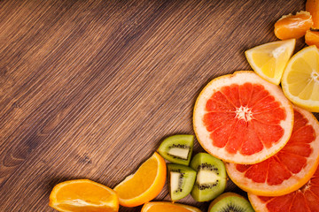 lemon, orange, kiwi, grapefruit, mandarin on a wooden surface. arrangement of sliced fruit. Top view with copy space for text