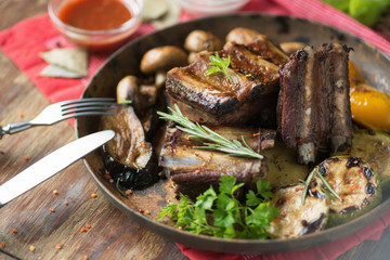 Ribs grilled in a frying pan with rosemary and mushrooms