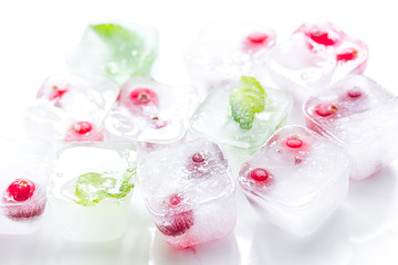 mint and red berries in ice cubes white background