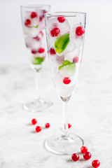 Ice cubes with berries and mint in glasses for summer drink white background