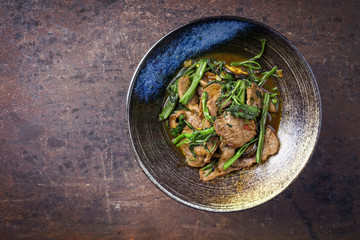 Traditional Stir Fried Thai Pad Nua with Morning Glory as close-up in a bowl