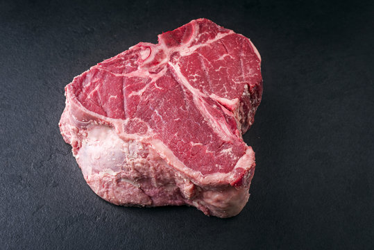 Raw dry aged Wagyu Porterhouse Steak as close-up on a black slate