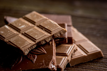 black and milk chocolate pieces wooden table background