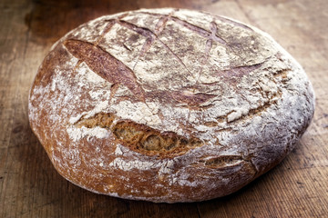 Frisch gebackenes Bauernbrot als close-up auf einem alten Holzbrett