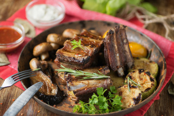 Ribs grilled in a frying pan with rosemary, mushrooms and zucchini