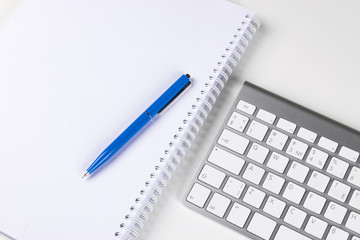 Wireless computer keyboard, notebook and pen on business office table