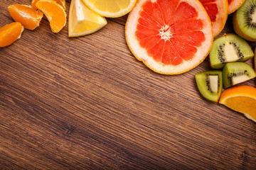 lemon, orange, kiwi, grapefruit, mandarin on a wooden surface. arrangement of sliced fruit. Top view with copy space for text