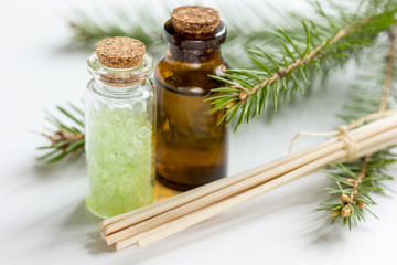 spa with organic spruce oil and sea salt in glass bottles on white table background