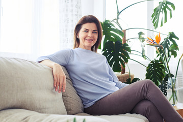Attractive madam sitting on sofa in bright living room