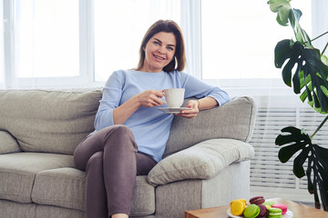 Pretty woman having rest on sofa with cup of coffee
