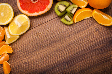 lemon, orange, kiwi, grapefruit, mandarin on a wooden surface. arrangement of sliced fruit. Top view with copy space for text