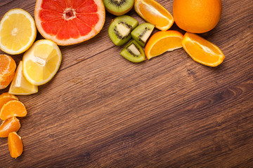 lemon, orange, kiwi, grapefruit, mandarin on a wooden surface. arrangement of sliced fruit. Top view with copy space for text