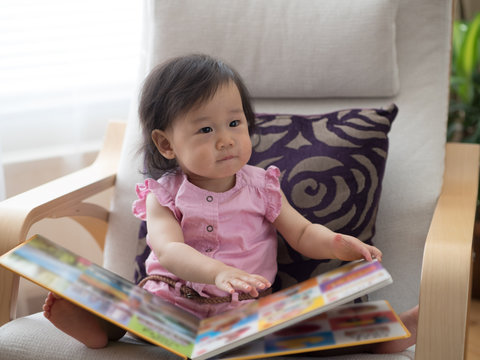 baby girl reading book at home