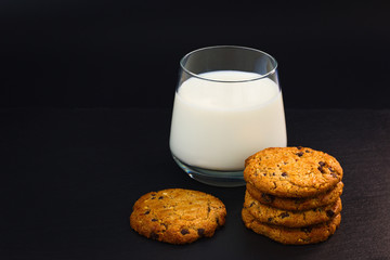 cookies and a glass of milk on black background 