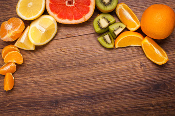 lemon, orange, kiwi, grapefruit, mandarin on a wooden surface. arrangement of sliced fruit. Top view with copy space for text