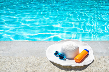 Fototapeta premium Summer hat, sunglasses and sunscreen near the pool