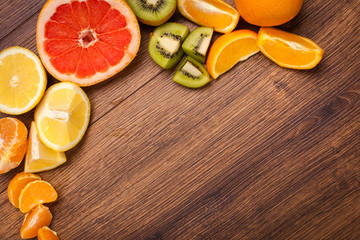 lemon, orange, kiwi, grapefruit, mandarin on a wooden surface. arrangement of sliced fruit. Top view with copy space for text