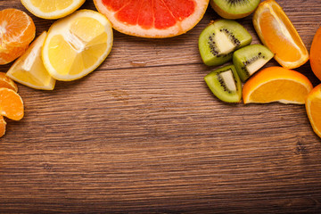 lemon, orange, kiwi, grapefruit, mandarin on a wooden surface. arrangement of sliced fruit. Top view with copy space for text