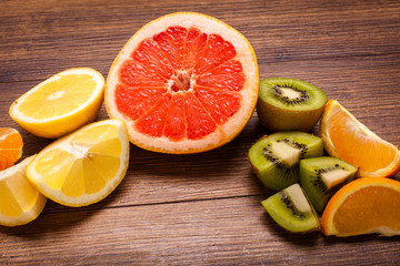 Fototapeta na wymiar lemon, orange, kiwi, grapefruit, mandarin on a wooden surface. arrangement of sliced fruit. Top view with copy space for text