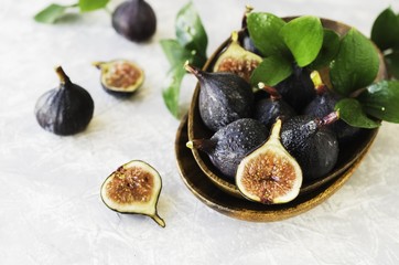dark blue Fresh figs in a wooden bowl on a white marble table, selective focus