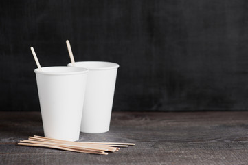 Background with two disposable cups and wooden sticks