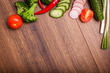 tomato, radish, cucumber, broccoli, onion, chili on a wooden surface. arrangement of sliced vegetables. Top view with copy space for text. Top view with copy space for text