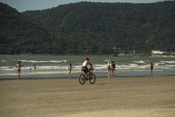 Pessoas pedalando na areia da praia