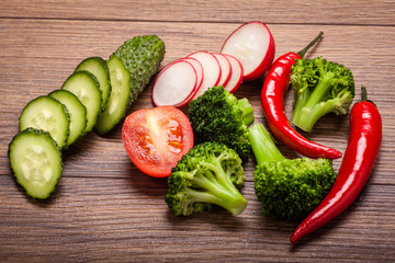 tomato, radish, cucumber and broccoli, chili on a wooden surface. arrangement of sliced vegetables