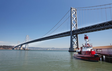 Oakland-San Francisco Bay Bridge with fire boat and blue sky.