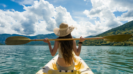 Young woman with long hair and hat resting during kayaking on lake © DarwelShots