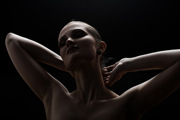 Black and white shot of woman posing sensually holding head up on black background