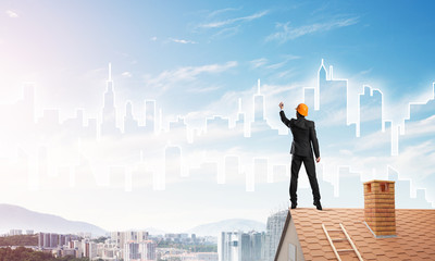 Man architect draw silhouette of modern city on blue sky. Mixed media