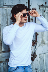 Man putting on sunglasses in front of the wooden door