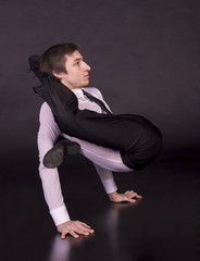 Extraordinary gymnast on a black background. The man with no bones. Studio photography of circus performers