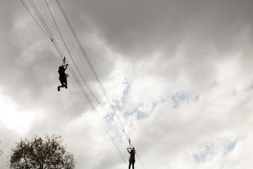 Silhouette of women playing zipline