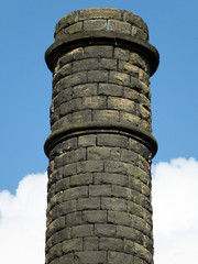 old stone mill chiney in yorkshire with blue sky and clouds