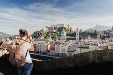 Austria. Salzburg. A young tourist girl takes pictures of the historic center of Salzburg: UNESCO...