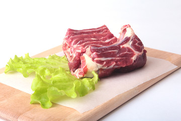 Raw beef edges and lettuce leaf on wooden desk isolated on white background from above and copy space. ready for cooking