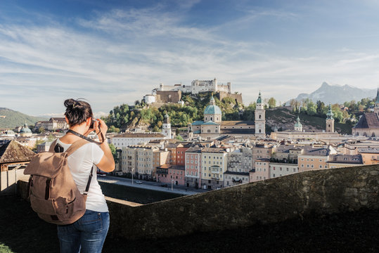 Austria. Salzburg. A young tourist girl takes pictures of the historic center of Salzburg: UNESCO World Cultural Heritage