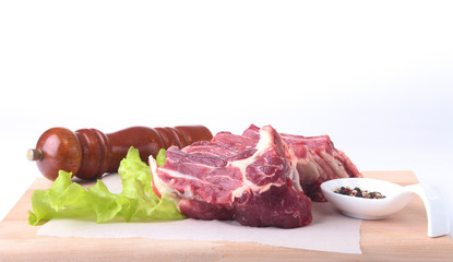 Raw beef edges, lettuce leaf, pepper grinder and spices on wooden desk isolated on white background from above and copy space. ready for cooking.