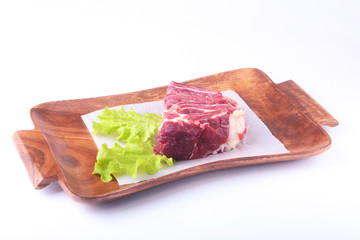 Raw beef edges and lettuce leaf on wooden desk isolated on white background from above and copy space. ready for cooking